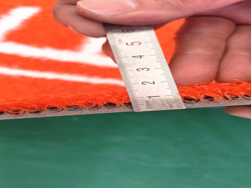 Hand pressing down on turf sample to test resilience